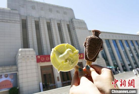 2021年7月30日，游客手拿“銅奔馬”“彩陶瓶”造型的雪糕，在甘肅省博物館前拍照打卡?！「哒?攝