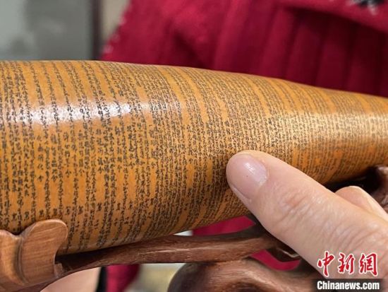 圖為長約二十公分的長條葫蘆雕刻佛教經文作品。　張婧 攝
