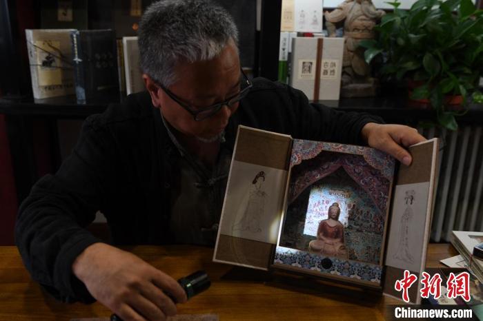 圖為讀者出版集團(tuán)讀者晉林工作室獨(dú)立出品人徐晉林，展示互動(dòng)性強(qiáng)的敦煌題材手工書。(資料圖) 楊艷敏 攝